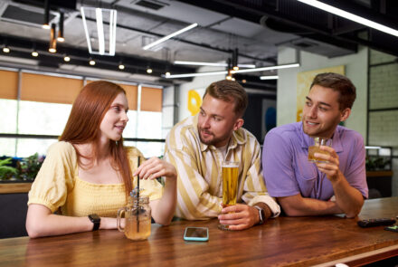portrait of young caucasian people meeting for the first time in a bar, beautiful women and handsome guys talk and have fun, drink beverages